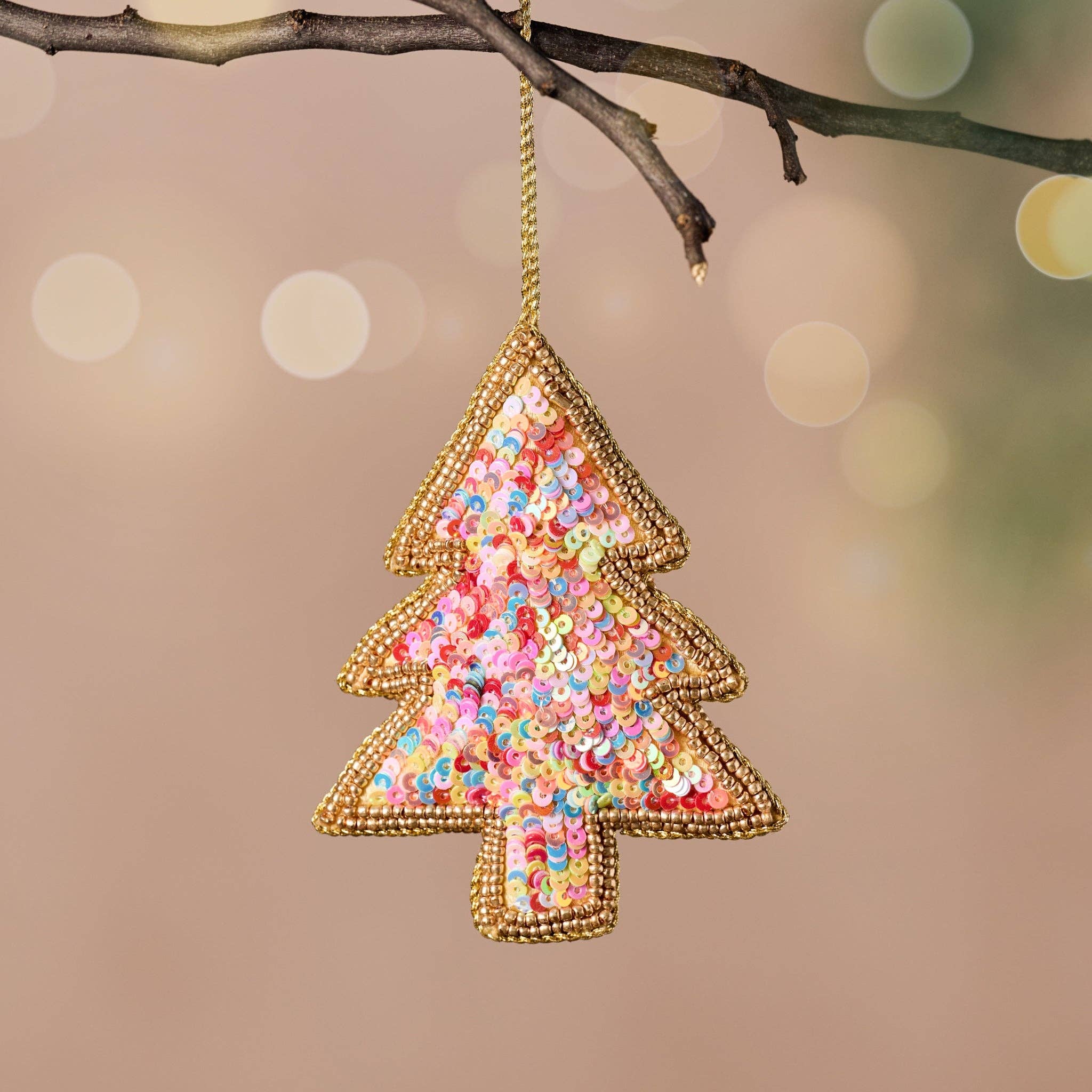 Decorative Christmas tree ornament with sequins hanging on a branch against a blurred holiday background.
