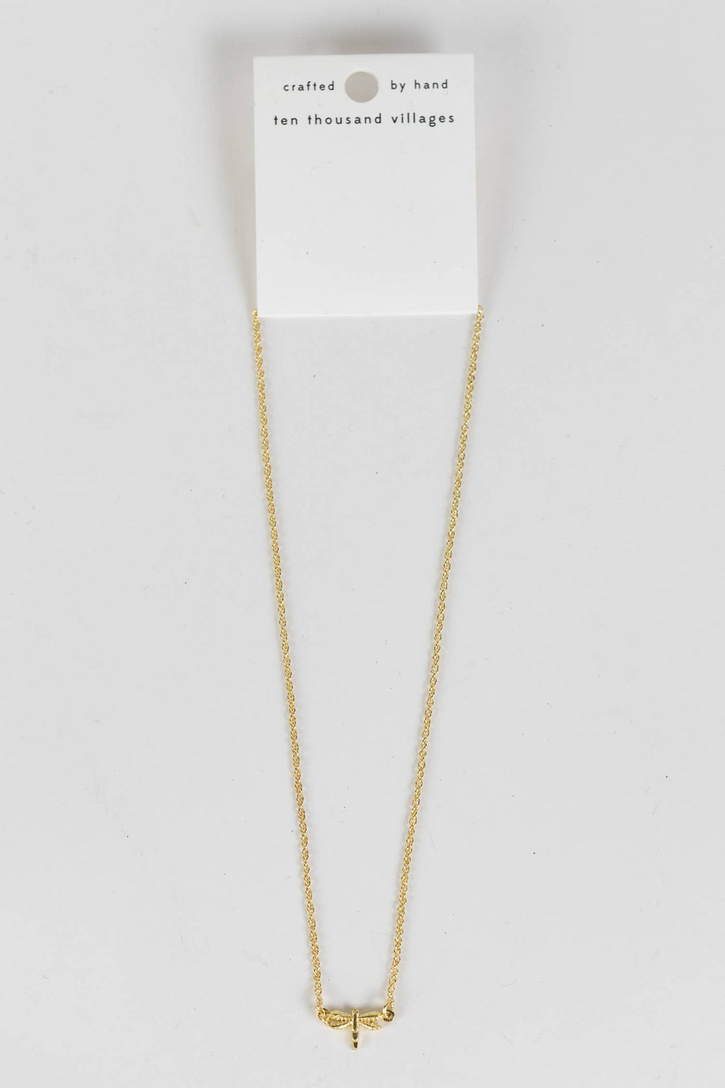 Delicate dragonfly charm necklace resting on neutral surface, handmade in India
