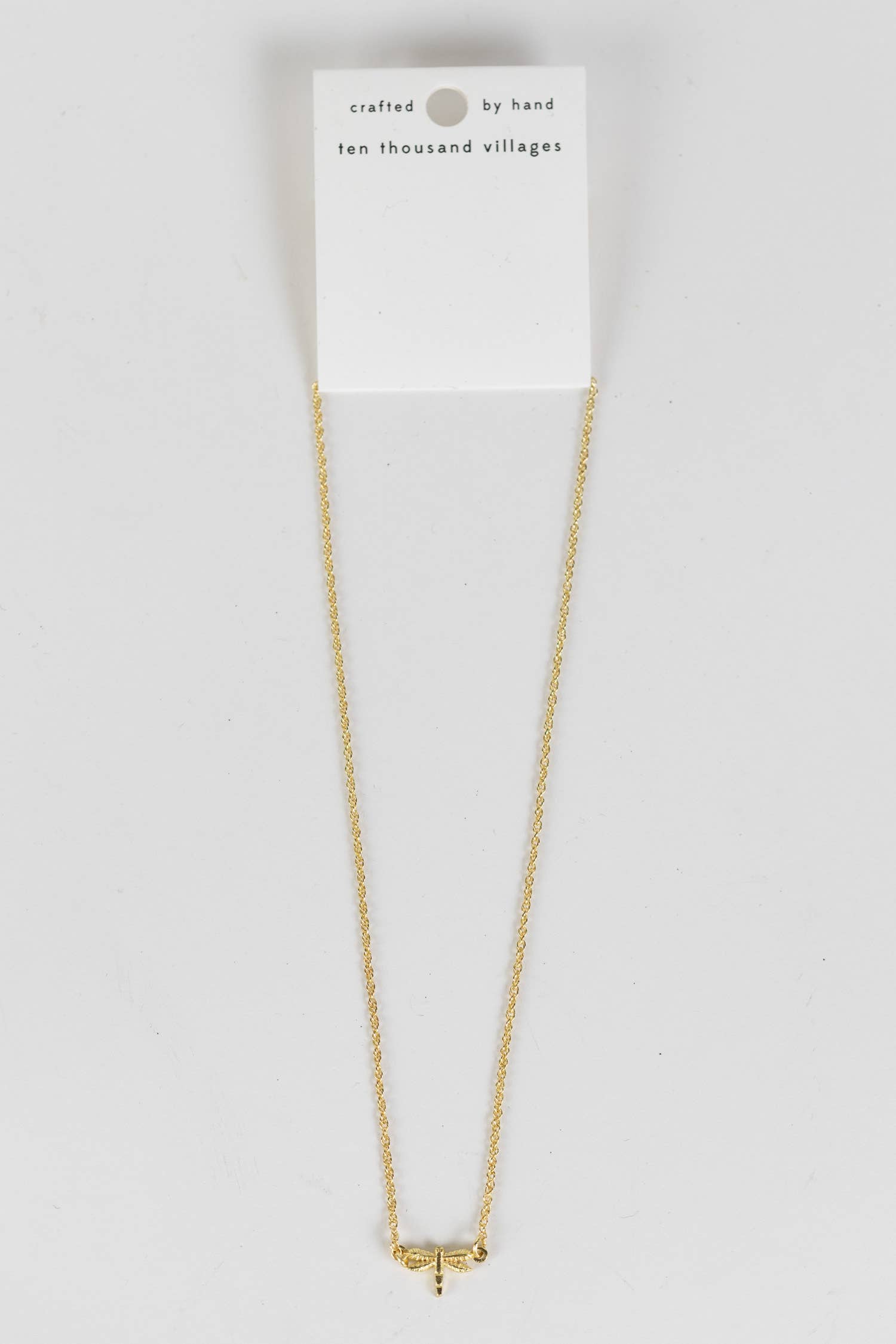 Delicate dragonfly charm necklace resting on neutral surface, handmade in India