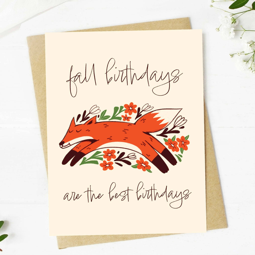 A greeting card with an illustration of a orange fox with fall leaves and the text 'fall birthdays are the best birthdays'. A kraft envelope is included.