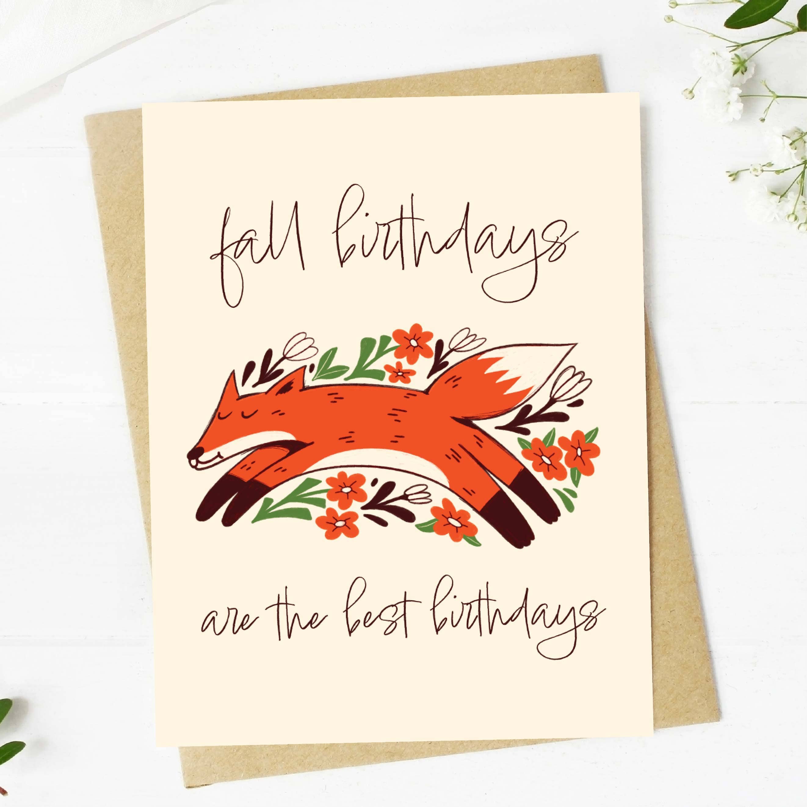 A greeting card with an illustration of a orange fox with fall leaves and the text 'fall birthdays are the best birthdays'. A kraft envelope is included.