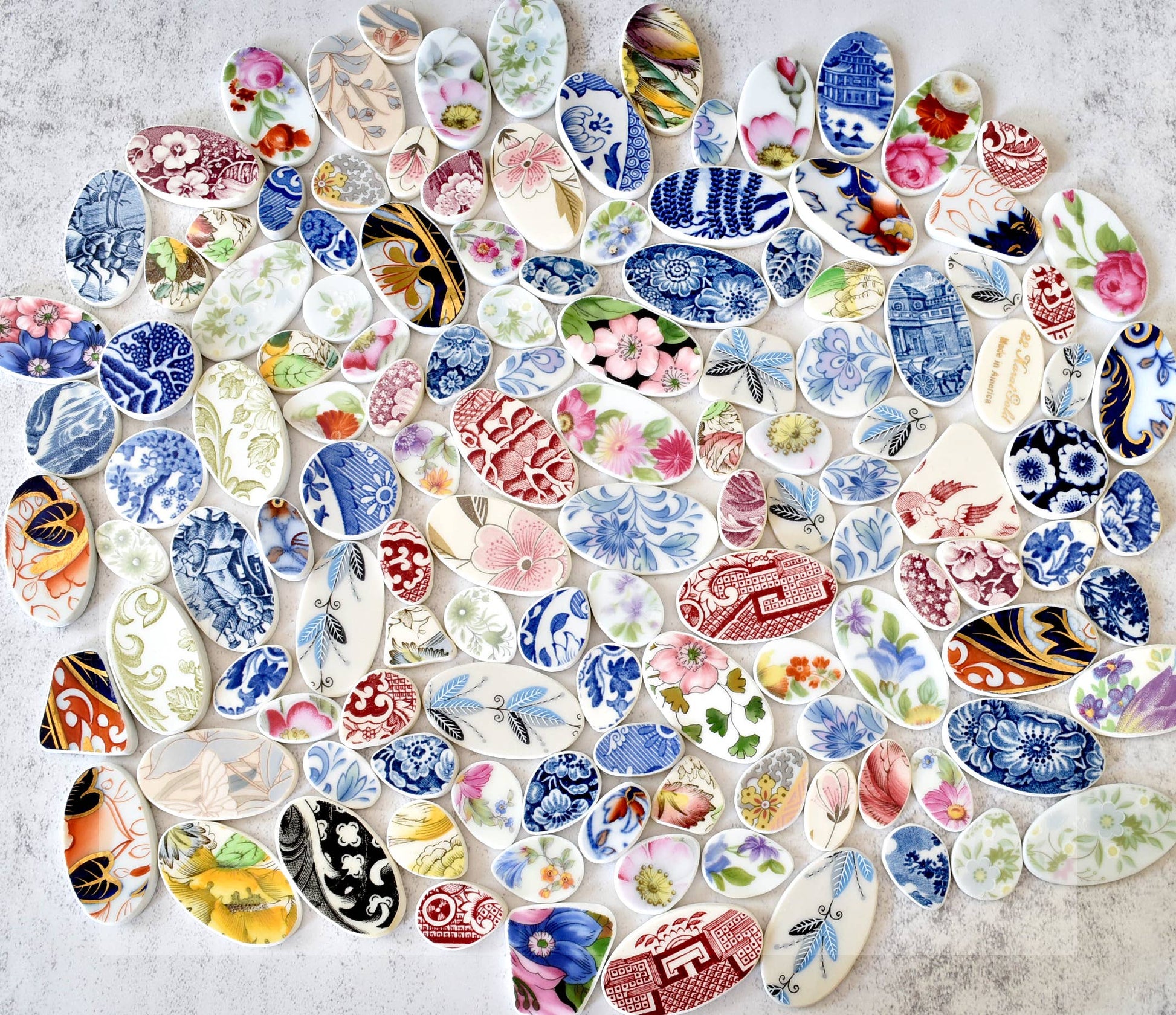 Collection of pieces of broken plate, that are sanded down and transformed into a necklace