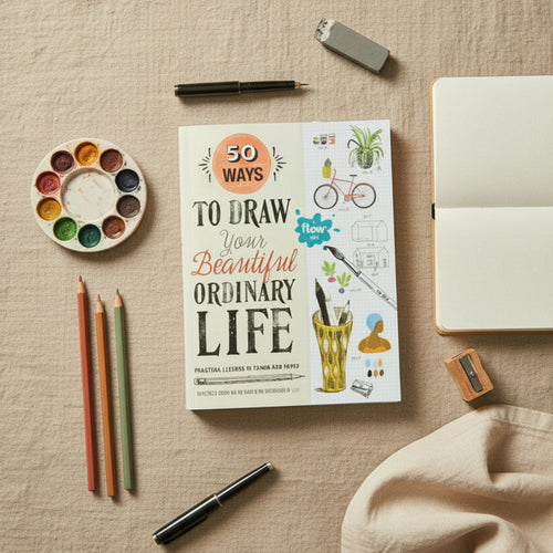Book titled '50 Ways to Draw Your Beautiful Ordinary Life' on a table with art supplies