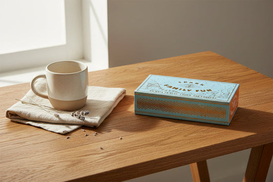 Box with 'Spark Family Fun' branding on a wooden table with a tea cup and other natural elements