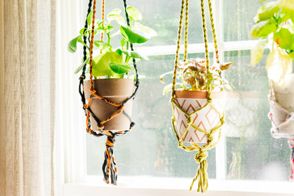 Three hanging planters with geometric patterns in front of a window.