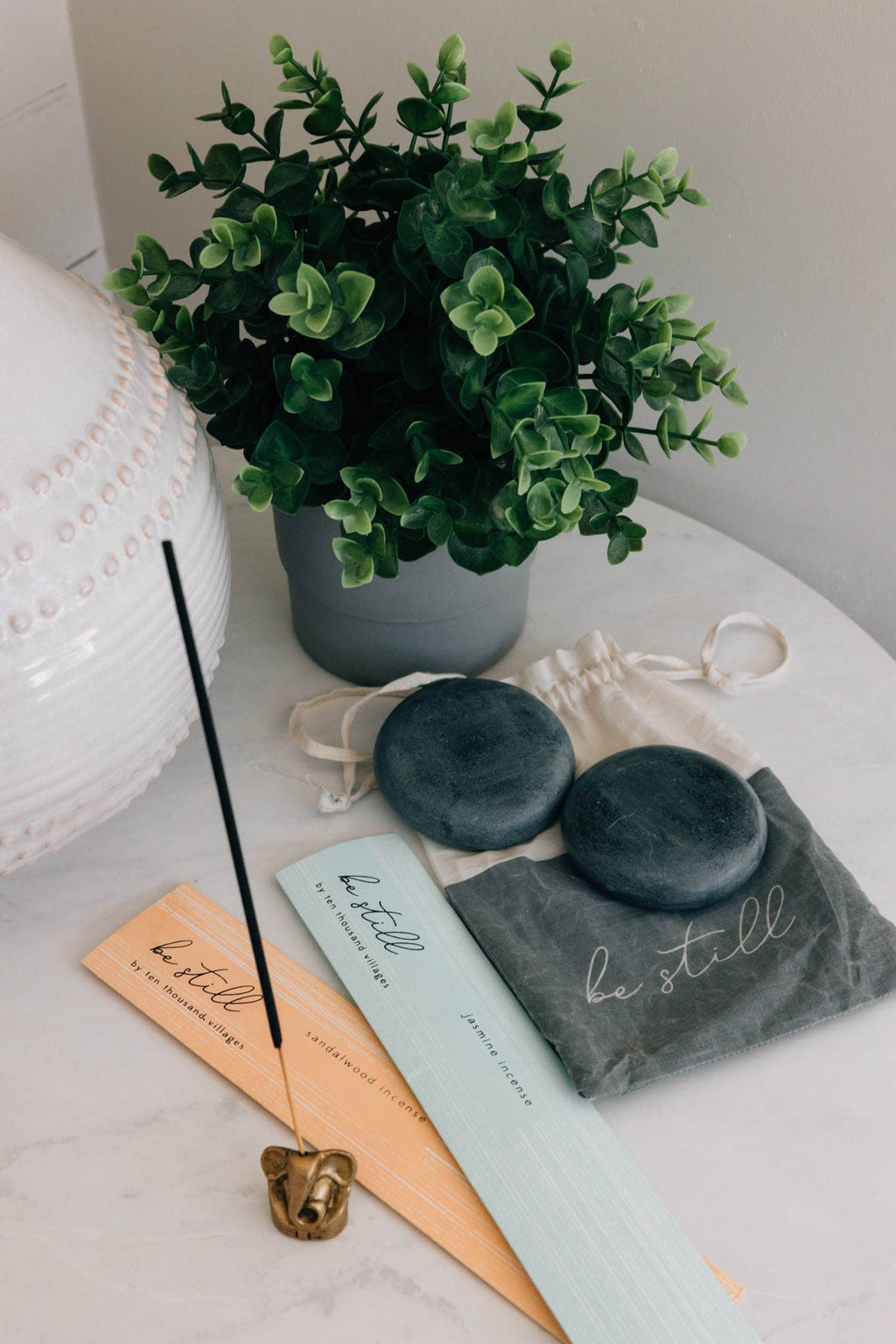 Decorative items including incense sticks, a plant, and a pouch on a surface.