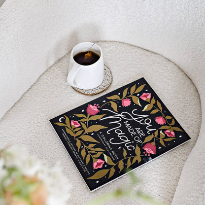 Book titled 'A Year of Magic' on a textured surface with a cup of coffee.