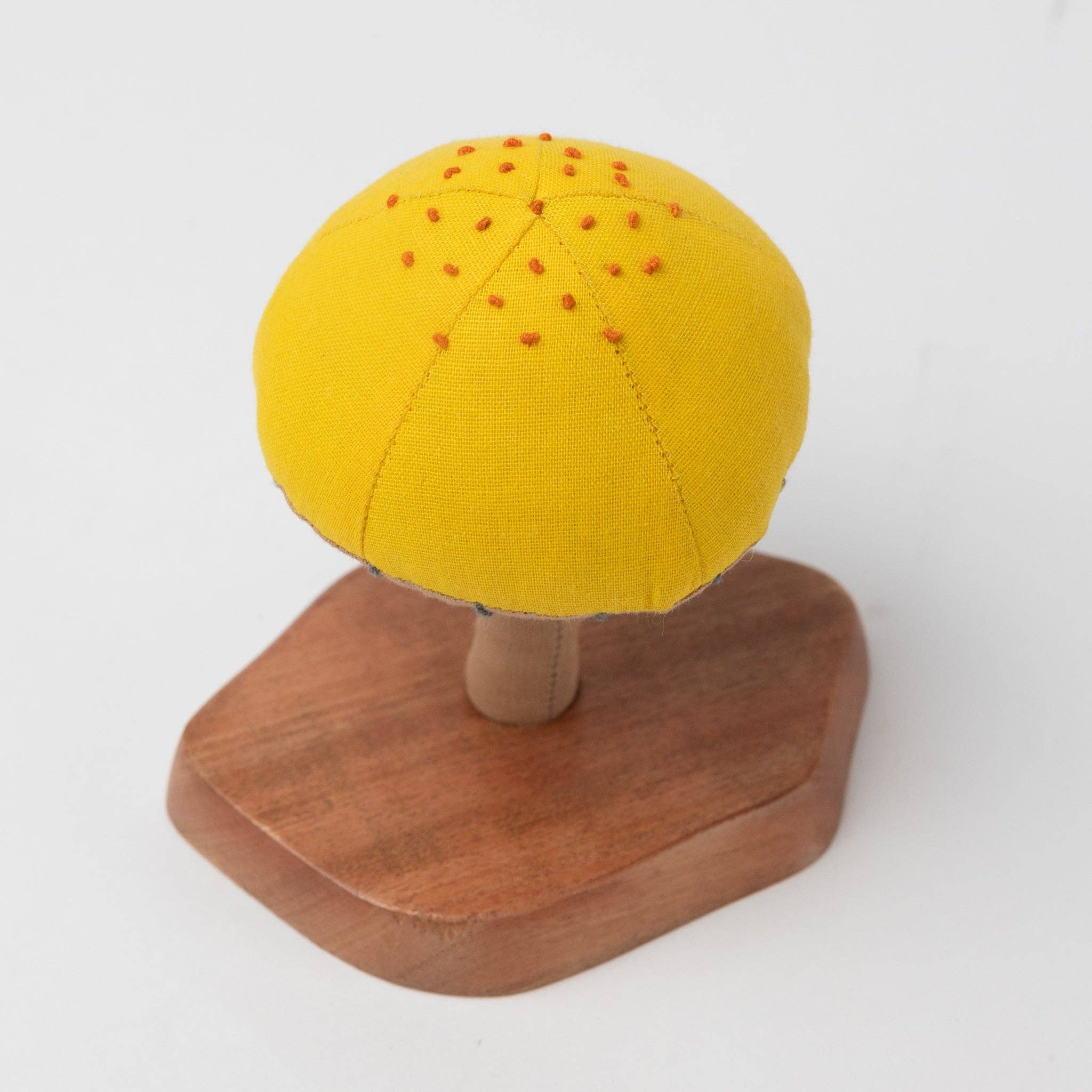 Close-up of hand-stitched mushroom cap details in warm tones