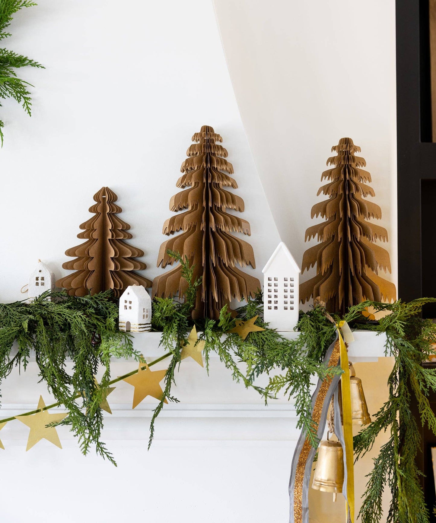 Decorative Christmas mantel with wooden trees, greenery, and gold accents.