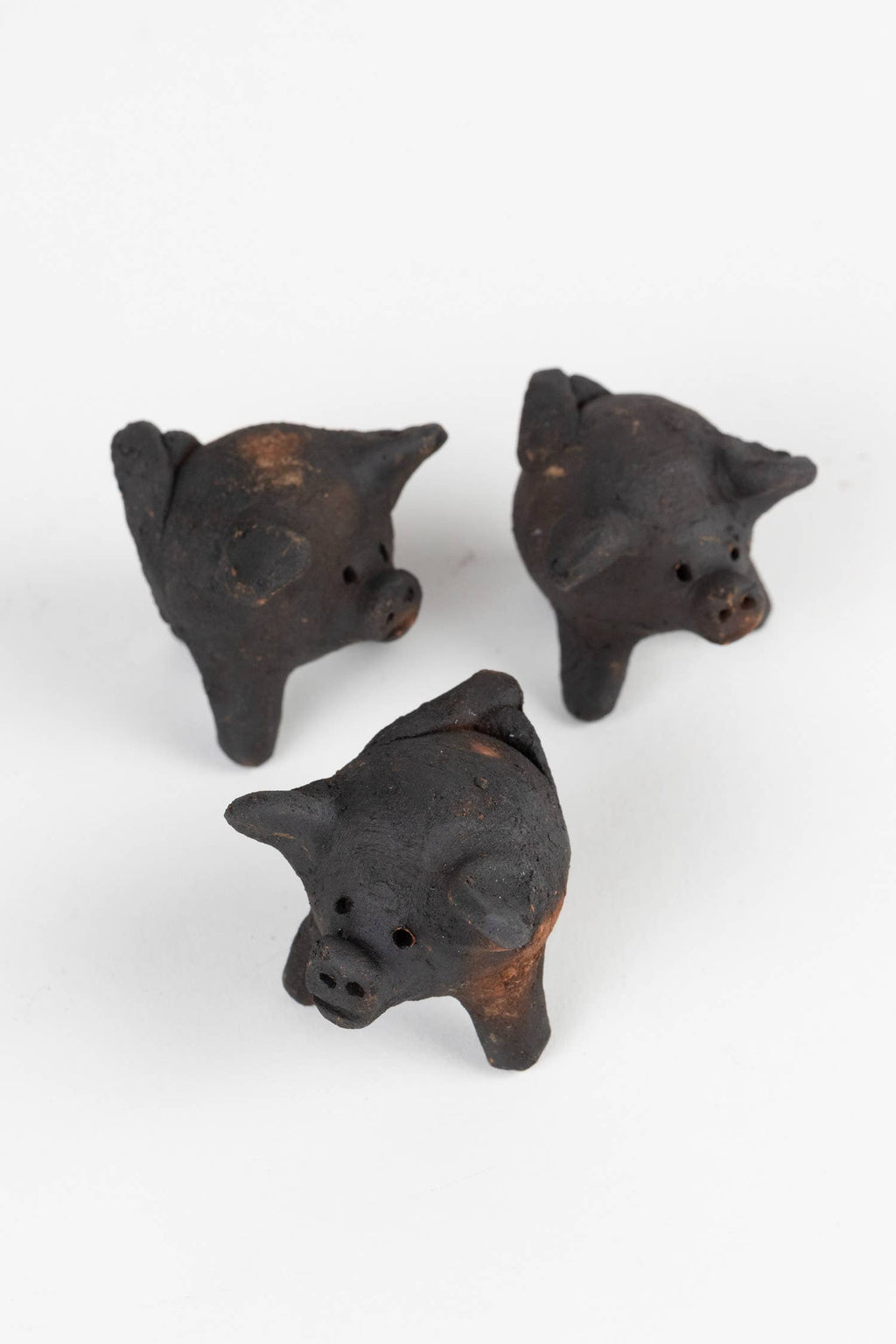 Three small black pig figurines on a white background