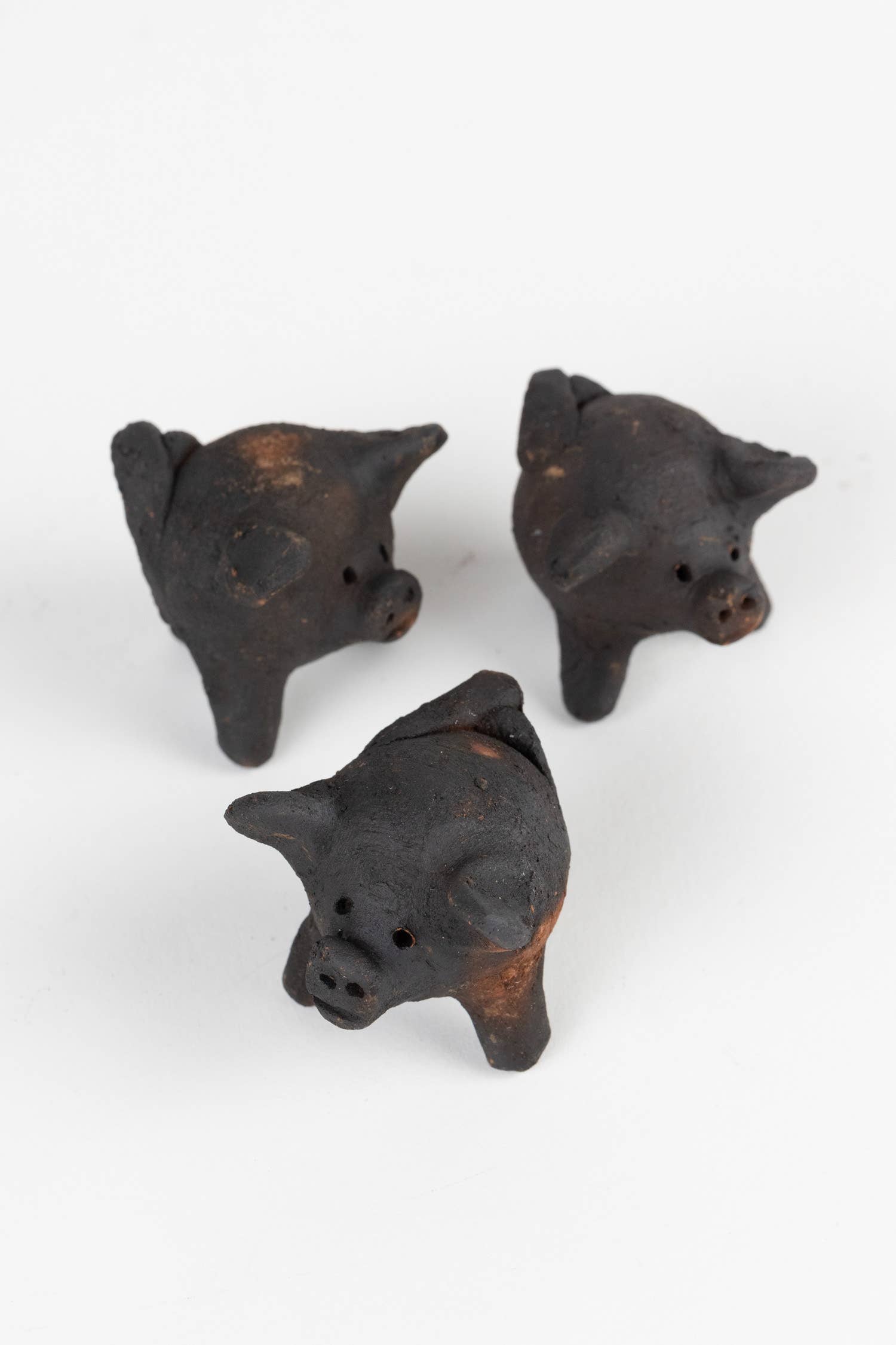 Three small black pig figurines on a white background