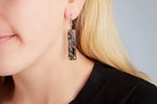 Close-up of artisan glass earrings showing unique swirls of color and enamel painting.