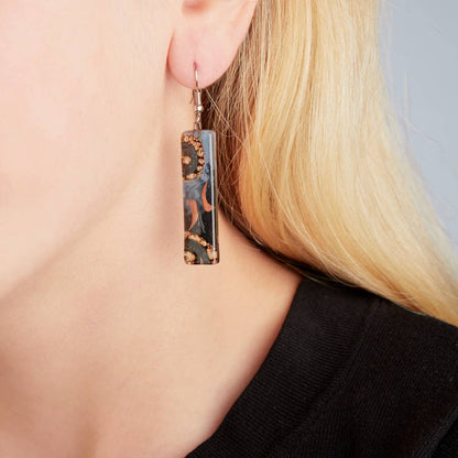 Close-up of artisan glass earrings showing unique swirls of color and enamel painting.