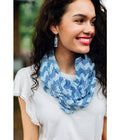 Woman wearing a blue patterned scarf with a blurred outdoor background