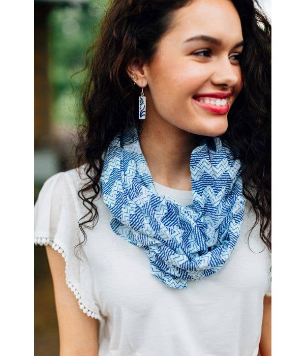 Woman wearing a blue patterned scarf with a blurred outdoor background