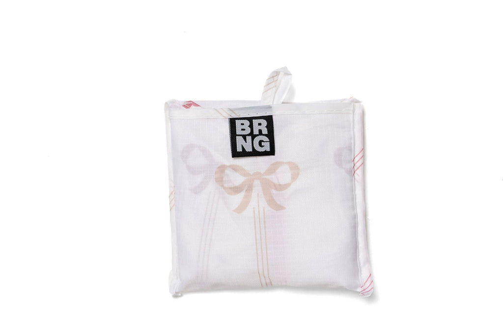 Vivi Daily Shopper from BRNG Bag folded up into a compact size with pink bows and a white background. 