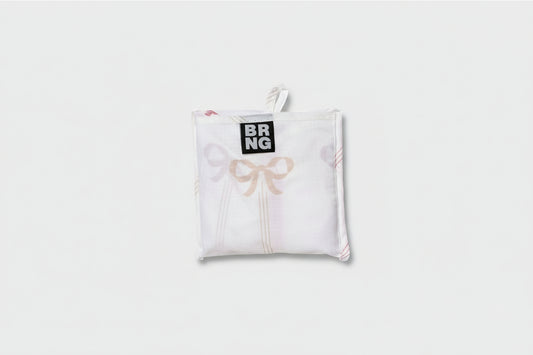 Vivi Daily Shopper from BRNG Bag folded up into a compact size with pink bows and a white background. 