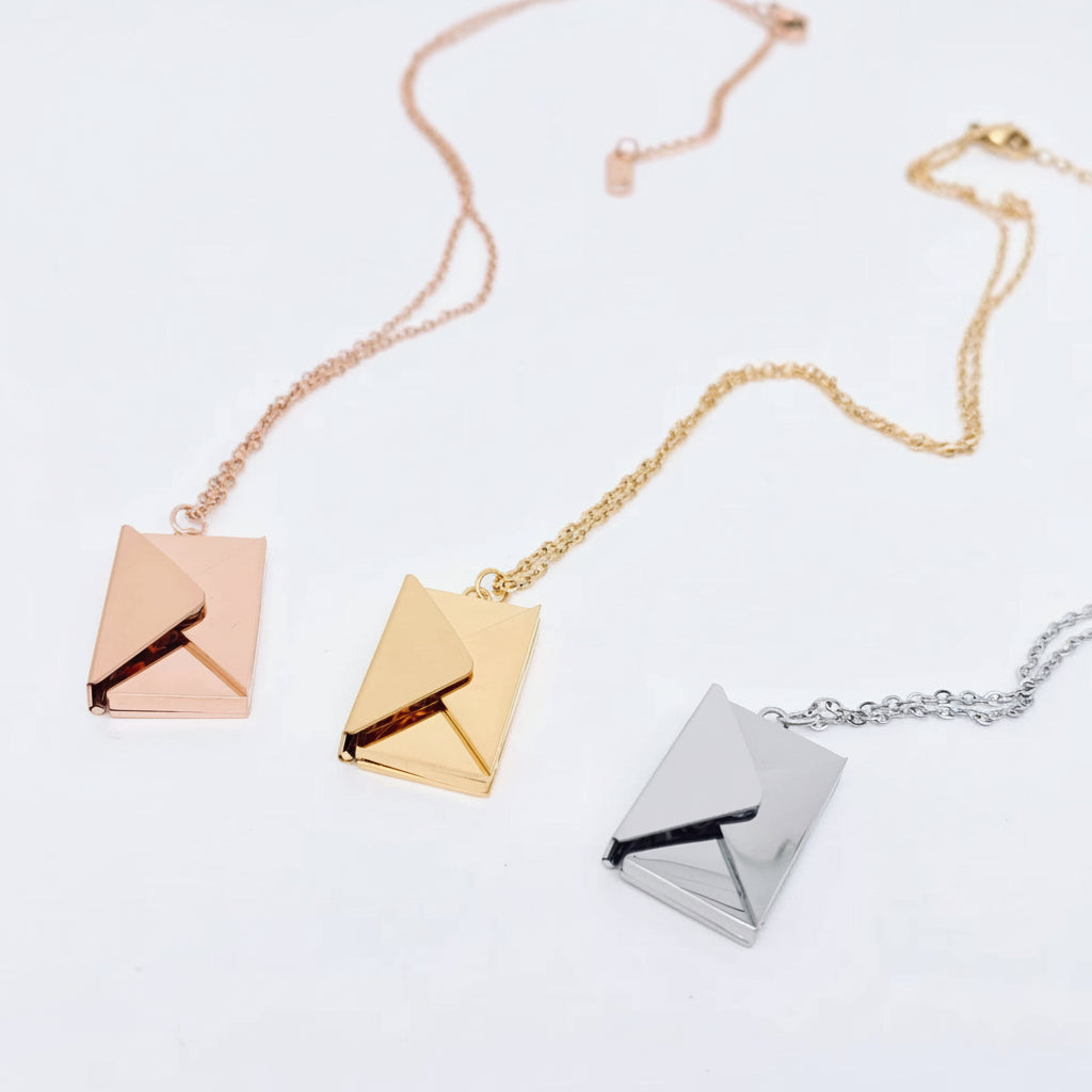 Three square pendant necklaces in rose gold, gold, and silver on a light gray background.