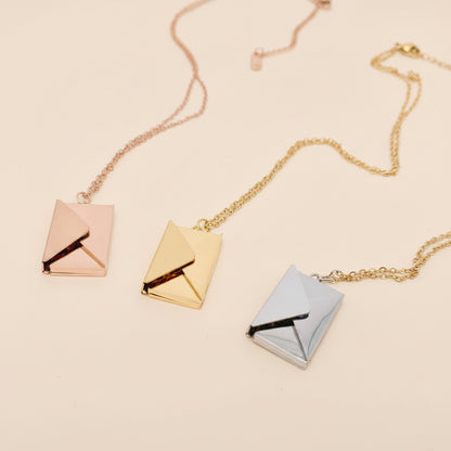 Three square pendant necklaces in rose gold, gold, and silver on a light gray background.