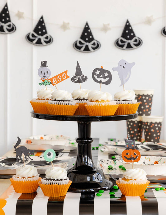 Halloween-themed cupcakes on a black cake stand with decorative toppers.
