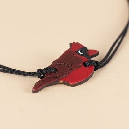 Cardinal-shaped pendant on a black cord against a white background