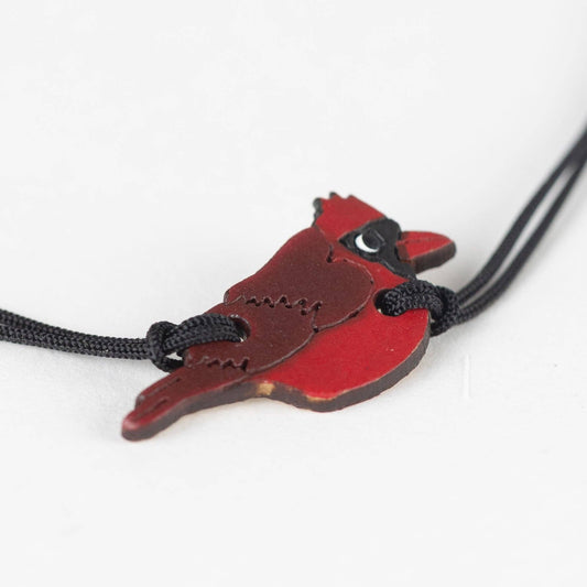 Cardinal-shaped pendant on a black cord against a white background