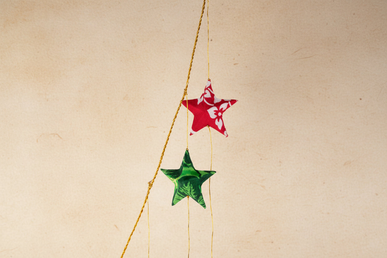 Two star-shaped decorations, one red and one green, hanging from a string against a white background.