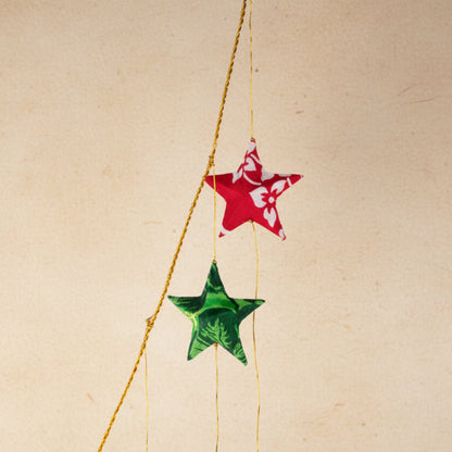Two star-shaped decorations, one red and one green, hanging from a string against a white background.