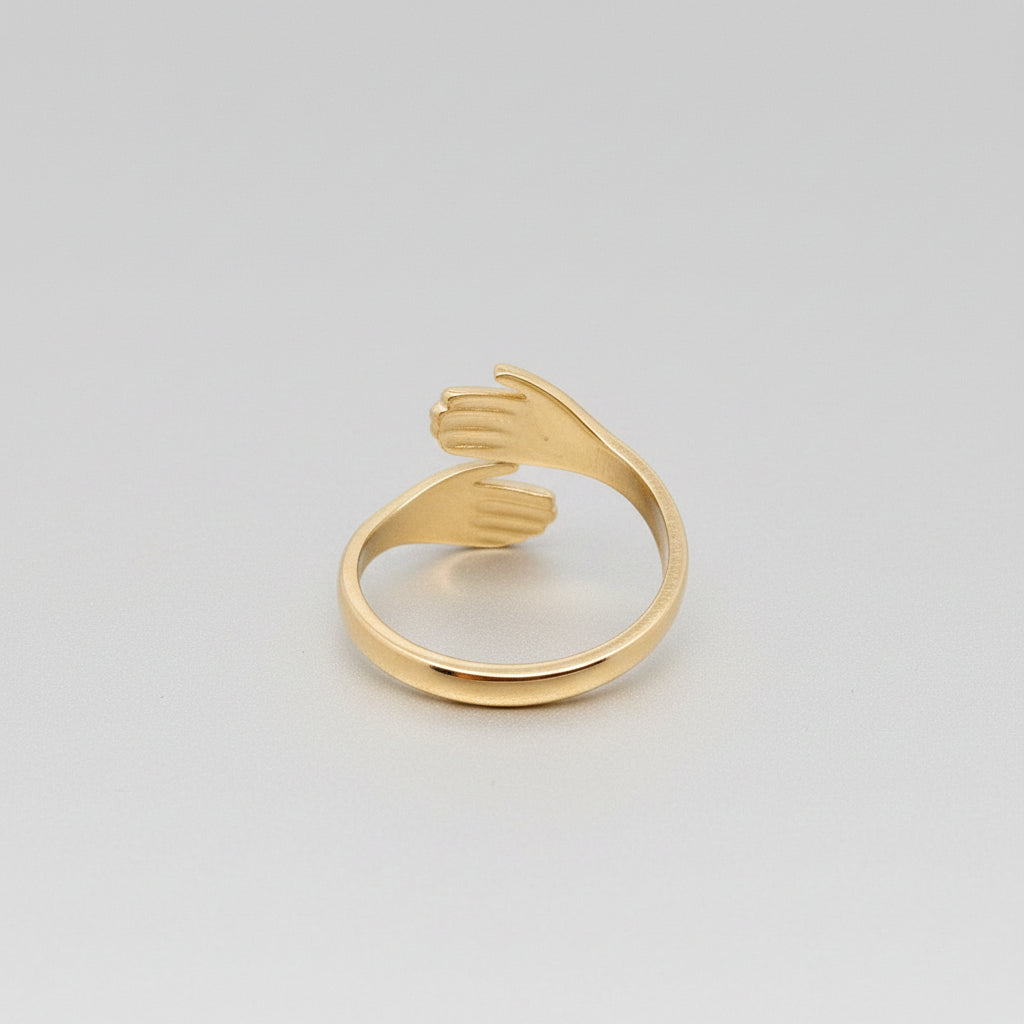 Gold ring shaped like a hand on a textured gray surface