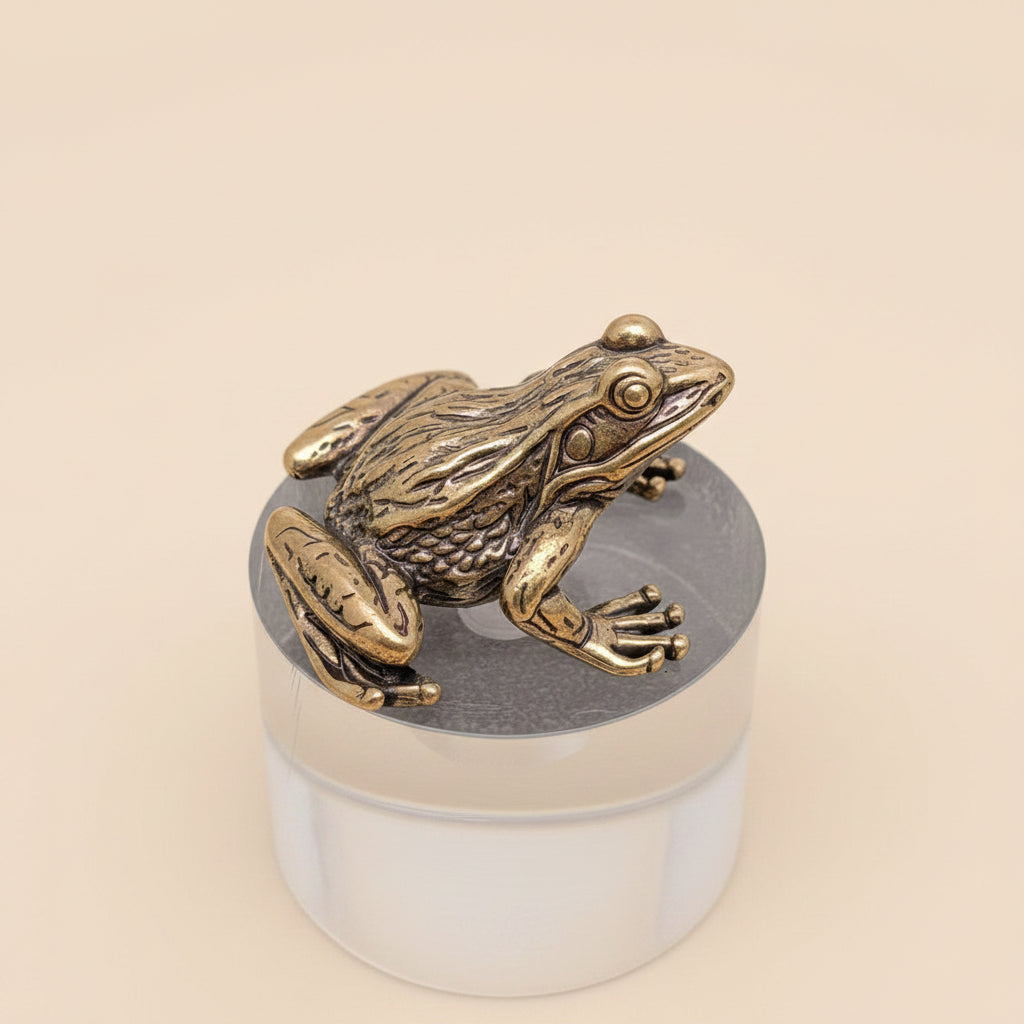 Bronze frog sculpture on a clear cylindrical base against a gray background