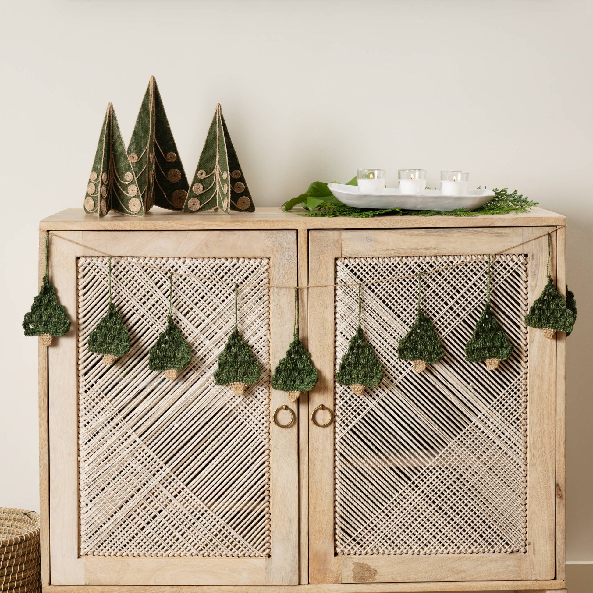 Holly Jolly Trees Crochet Garland draped across a buffet with other festive ornaments and decor with a neutral holiday background