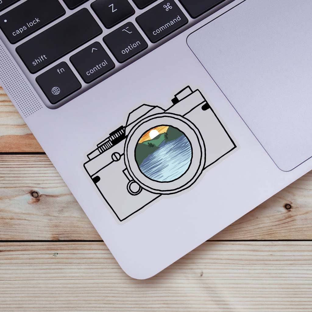 Close up of the Adventure Awaits Camera sticker on a laptop.