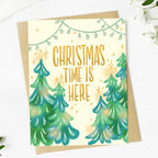 Greeting card with Christmas trees and 'Christmas time is here' text on a white background