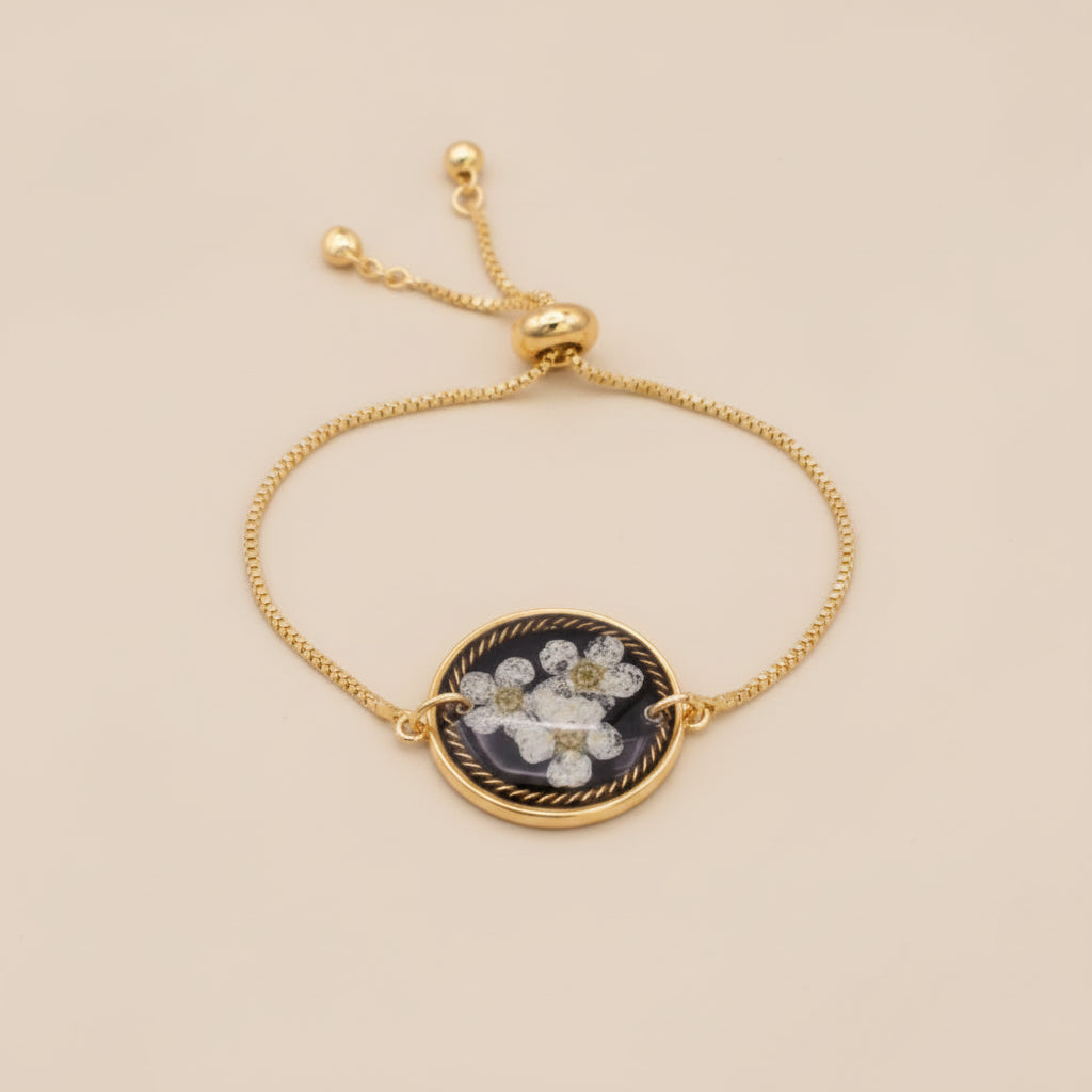 Gold necklace with a floral pendant on a pink textured background