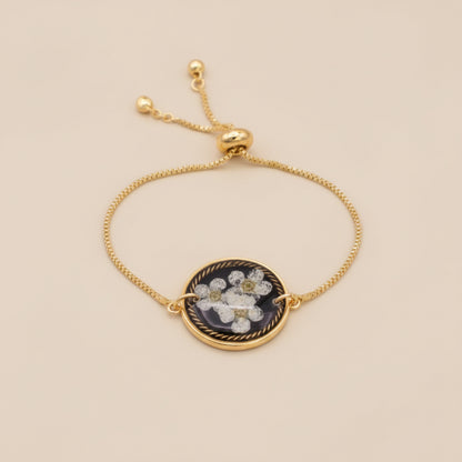Gold necklace with a floral pendant on a pink textured background