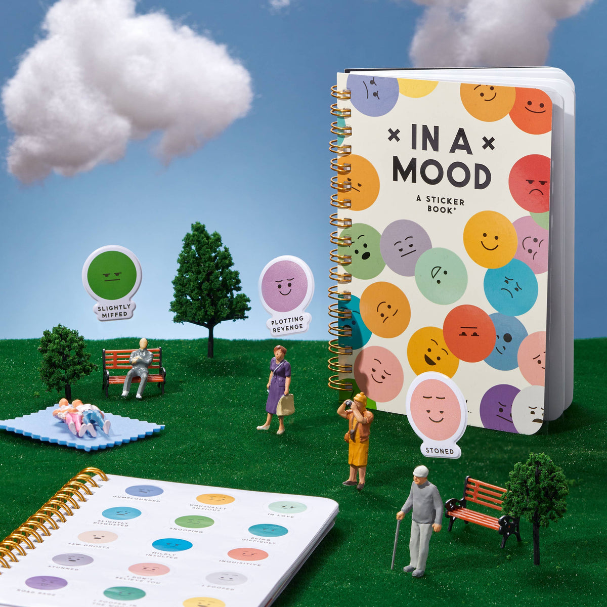 Sticker book titled 'In a Mood' with colorful emoji faces on a miniature park setting.