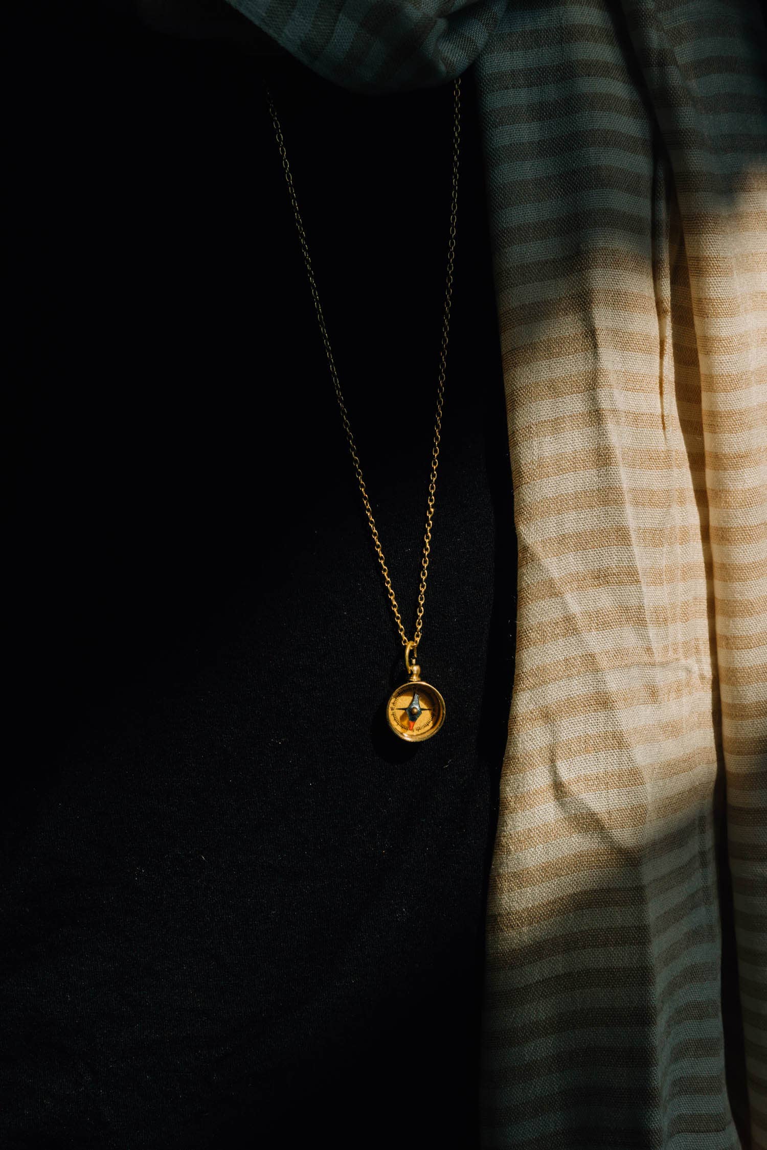 Gold necklace with a pendant on a dark background