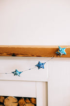Embroidered Star Garland hanging from a mantel over a fireplace
