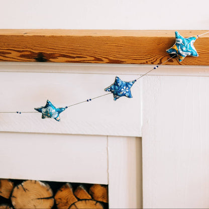 Embroidered Star Garland hanging from a mantel over a fireplace