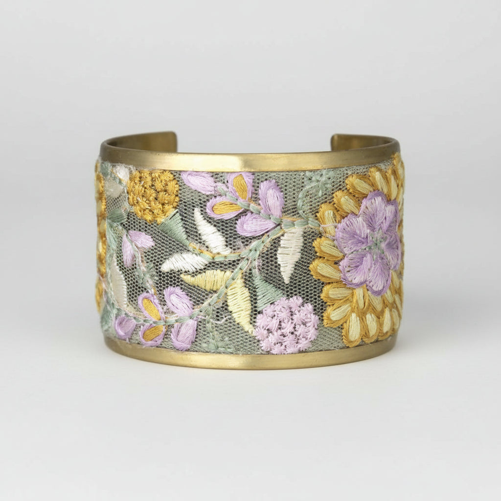 Gold bracelet with floral embroidery on a white background