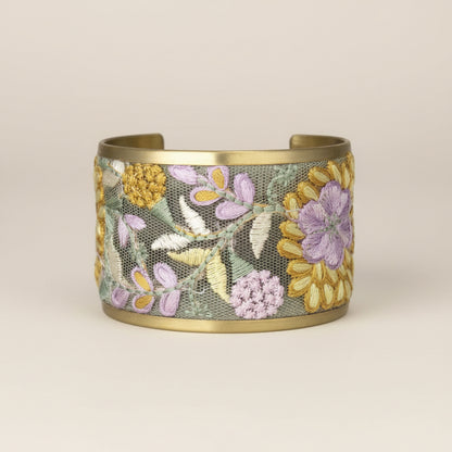 Gold bracelet with floral embroidery on a white background