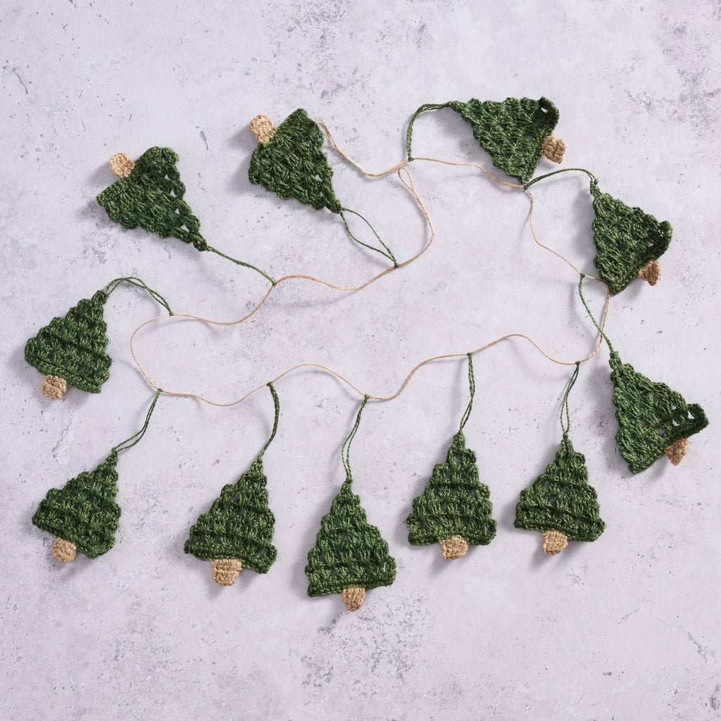 The Holly Jolly Trees Crochet Garland laid out on a marble countertop showcasing the length and amount of trees on each garland