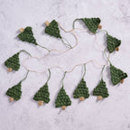 The Holly Jolly Trees Crochet Garland laid out on a marble countertop showcasing the length and amount of trees on each garland