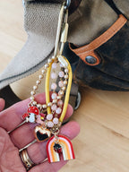 Close up view of rainbow and mushroom enamel charms hanging from bright yellow paracord