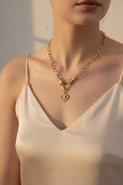 Gold necklace with a pendant worn on the neck, against a neutral background
