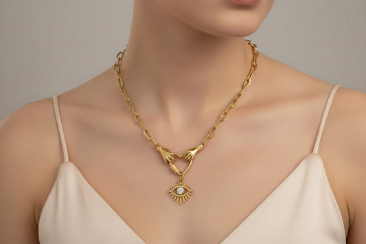 Gold necklace with a pendant worn on the neck, against a neutral background