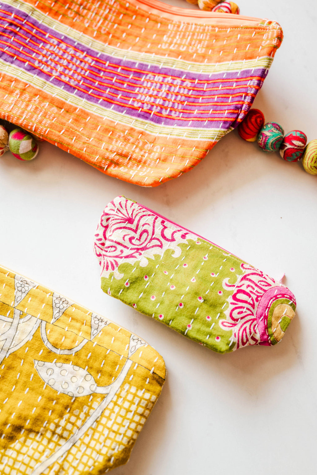 Three colorful fabric pouches on a light background