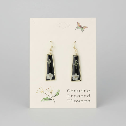 Black teardrop earrings with floral details on a beige card with botanical illustrations.