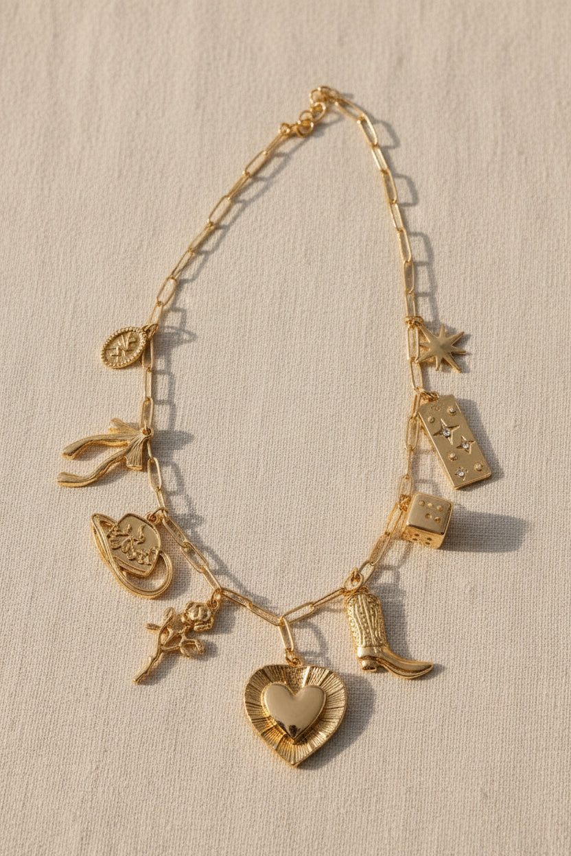 Gold charm bracelet with various charms on a beige background