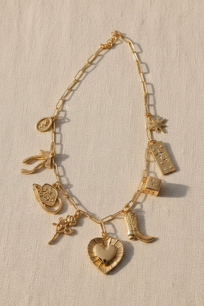 Gold charm bracelet with various charms on a beige background